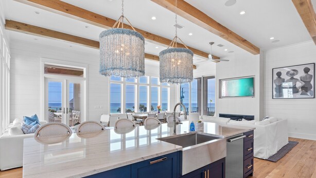 Een moderne keuken met een groot eiland, blauwe kastjes en uitzicht op de oceaan.