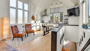 A modern kitchen with white cabinetry, a large window, and a dining area with leather chairs. - 2-Story Guesthouse w/ Private Deck in NE PDX (Portland)