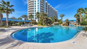 A hotel with a large pool, palm trees, and a clear blue sky. - 2026 Updated 2BR | Largest Lagoon Size Pool (Destin)