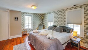 Un dormitorio con cama, mesita de noche, lámpara y ventana con persianas.