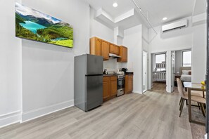 Una cocina moderna con armarios de madera, un refrigerador de acero inoxidable y un televisor de pantalla plana grande montado en la pared.
