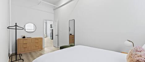 Una camera da letto moderna con un letto grande, una cassettiera, uno specchio e un cabina armadio.