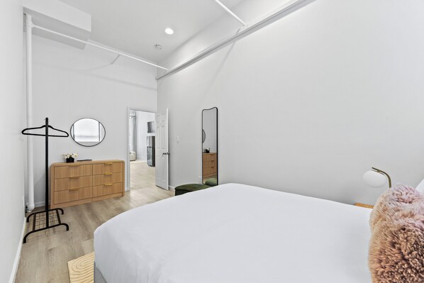 Un dormitorio moderno con una cama grande, un aparador, un espejo y un vestidor.