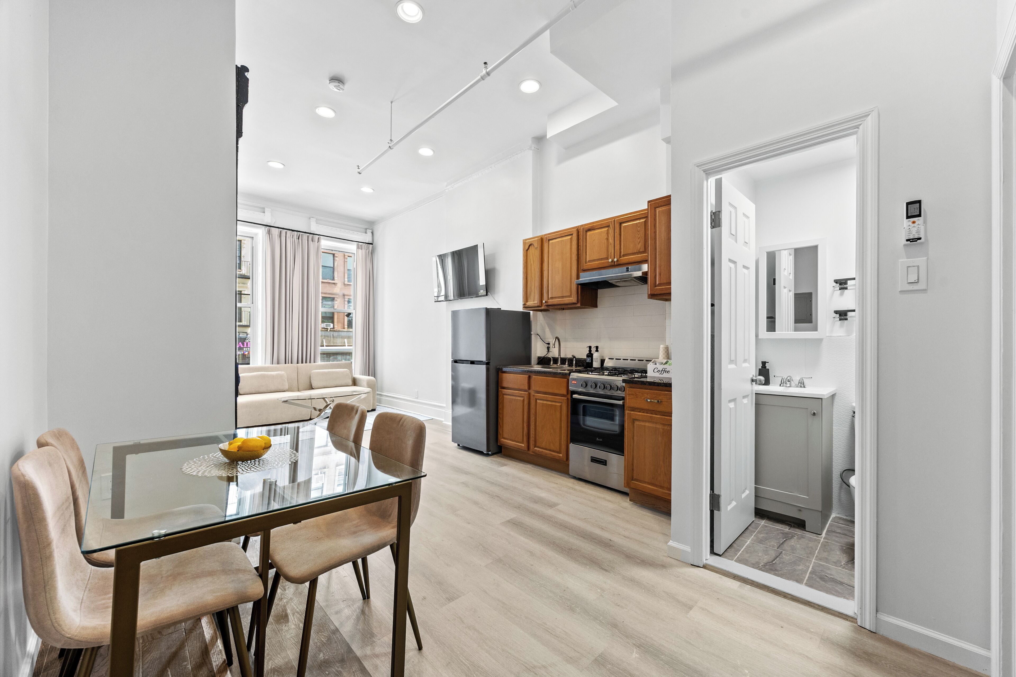 A modern kitchen with wooden cabinets, a stainless steel refrigerator, and a built-in oven.