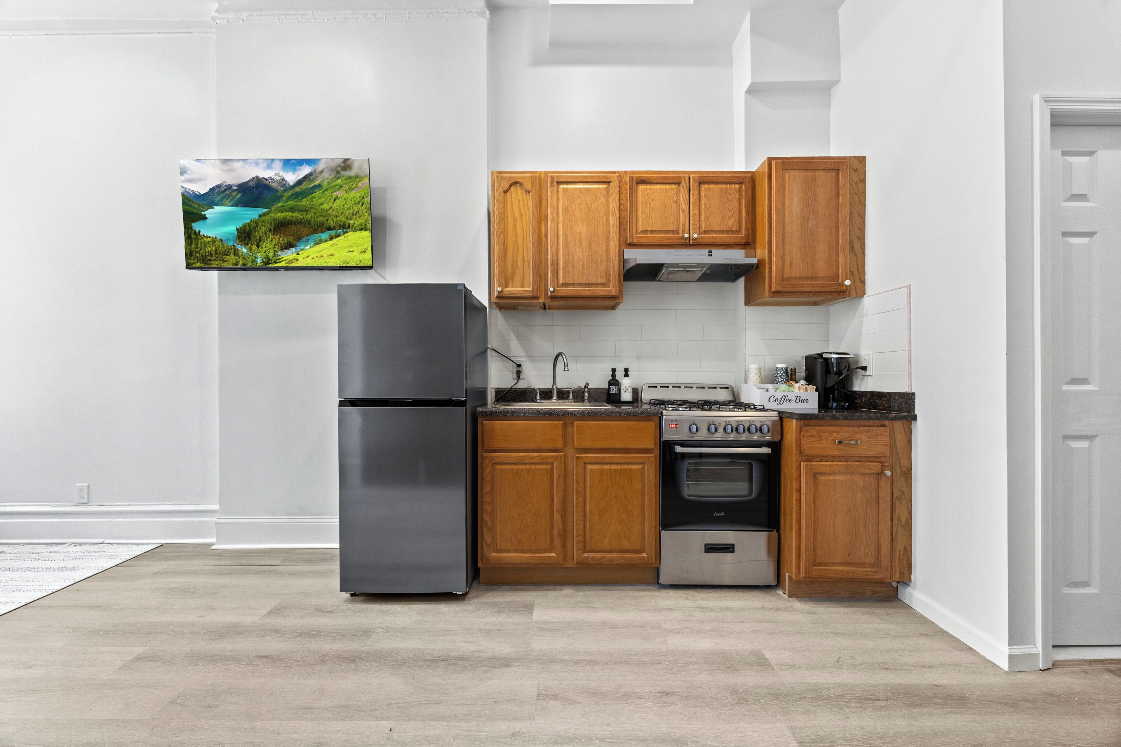 A kitchen with wooden cabinets, a stainless steel refrigerator, a stove, and a sink.