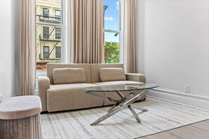 A modern living room with a beige sofa, a glass coffee table, and a patterned rug.