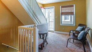 Un escalier avec une rampe blanche, un banc en bois et une chaise avec un coussin.