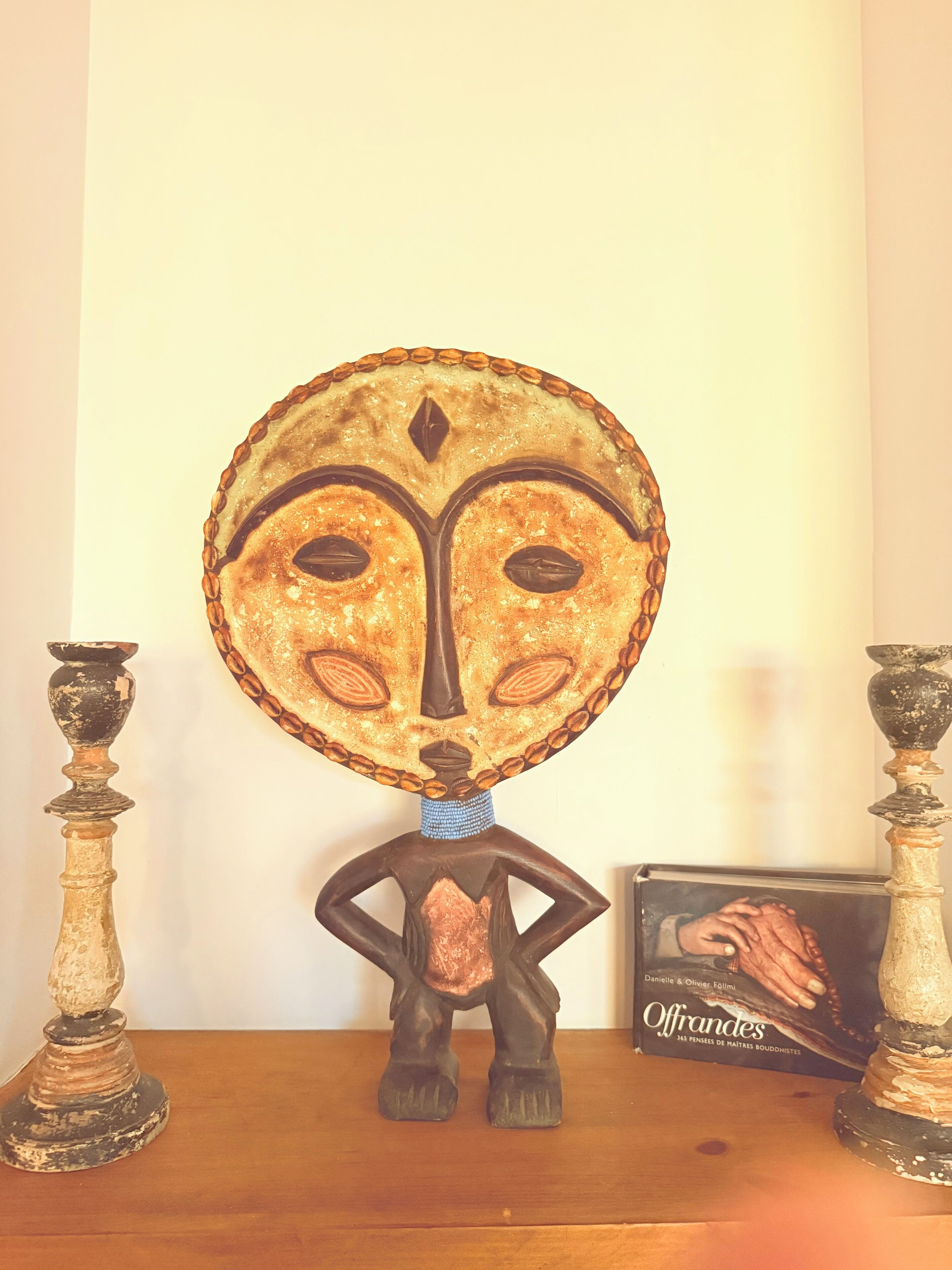 Une sculpture décorative, dotée d’un sommet circulaire et d’une figure en dessous, posée sur une surface en bois.