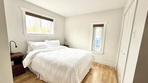 Une chambre à coucher avec un lit, deux tables de chevet, une fenêtre et une porte.