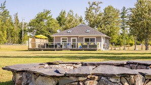 Une maison à deux étages avec des fondations en pierre, un patio couvert et une pelouse.