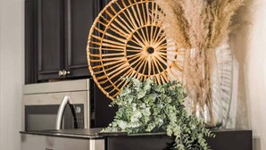 A kitchen with dark cabinets, a stainless steel refrigerator, and a decorative fan with a plant arrangement. - The Hide-Out! A Boho Cabin AC- Wi-fi (Mi-Wuk Village)