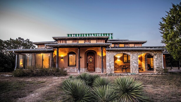 A two-story house with a stone facade, multiple arched doorways, and a covered patio area. - Sacred River Retreat For 12ppl (Hunt)