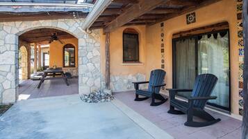 A covered patio area with stone walls, wooden beams, and a stone bench.