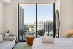 A hotel room with a large sliding glass door leading to a balcony with a city view. - Crosby Miami WTC Studio City Haven #2415 (Miami)