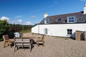 A white house with a gravel patio, wooden furniture, and a clear sky. - Luxury Island Living in the Heart of Gigha (Isle of Gigha)