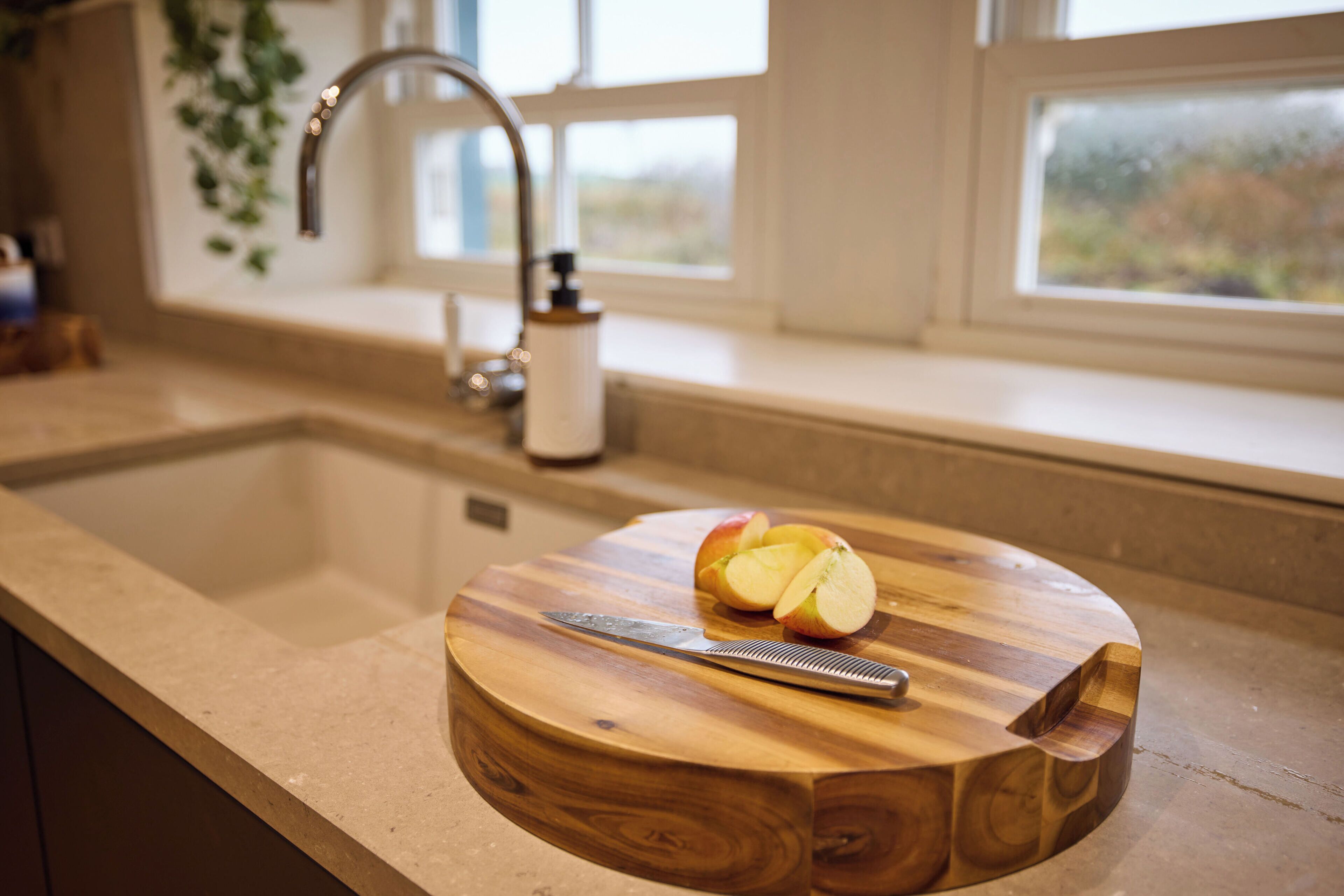 A kitchen counter with a wooden cutting board holding a knife and apple slices.
