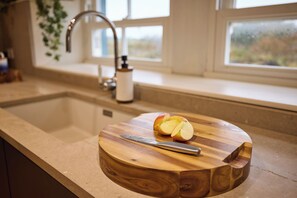 A kitchen counter with a wooden cutting board holding a knife and apple slices. - Luxury Island Living in the Heart of Gigha (Isle of Gigha)