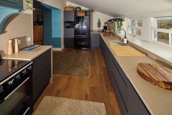 A modern kitchen with a built-in oven, a refrigerator, and a wooden countertop.