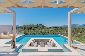 Ein Poolbereich mit Sitzgelegenheiten und Blick auf eine hügelige Landschaft.