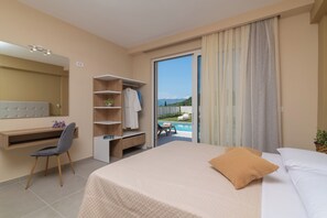 A hotel room with a bed, a desk, a chair, a wardrobe, and a view of a pool and mountains. - Spartakos Villa Resort (Zakynthos)
