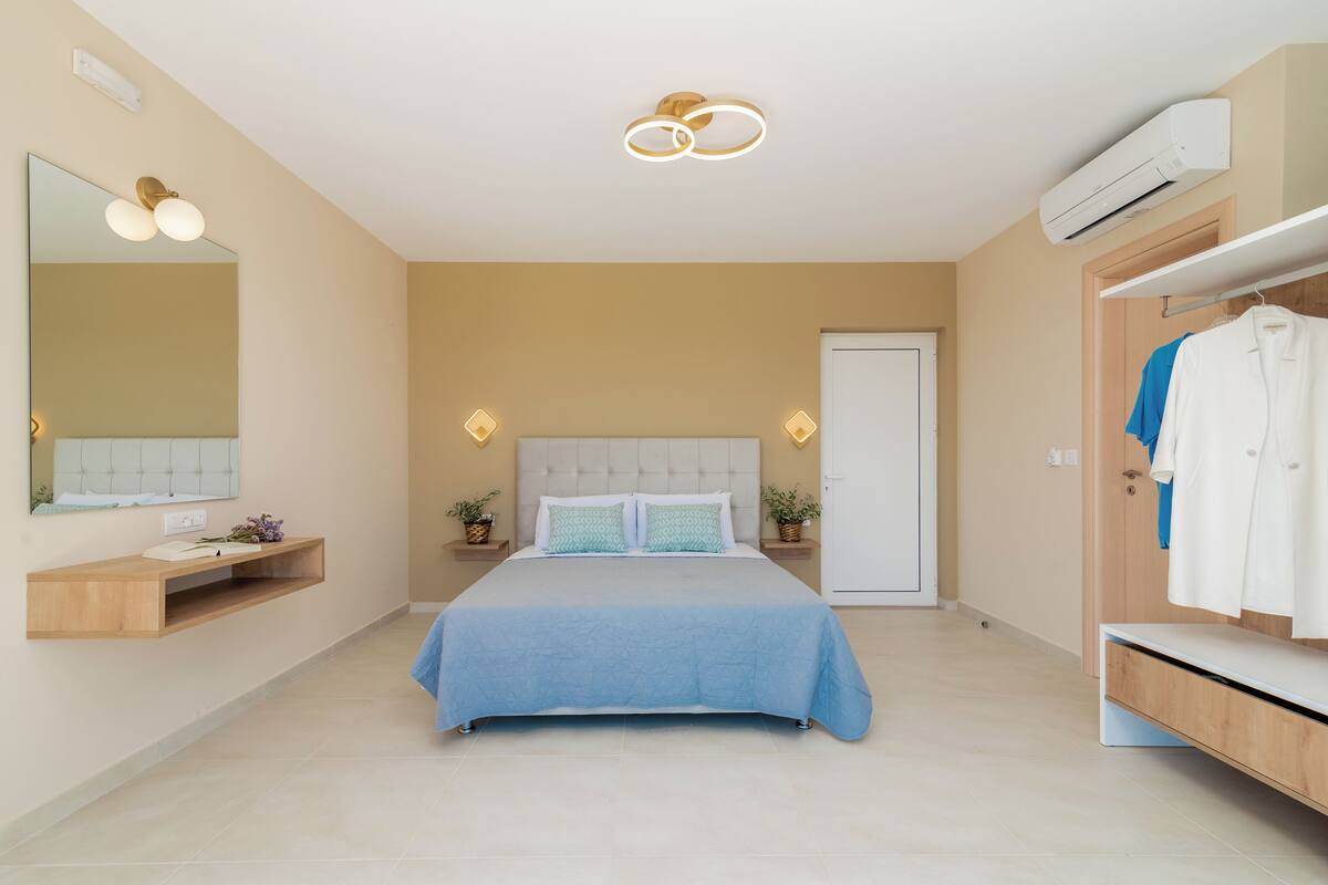 A modern bedroom with a bed, a vanity, a wardrobe, and a mirror.
