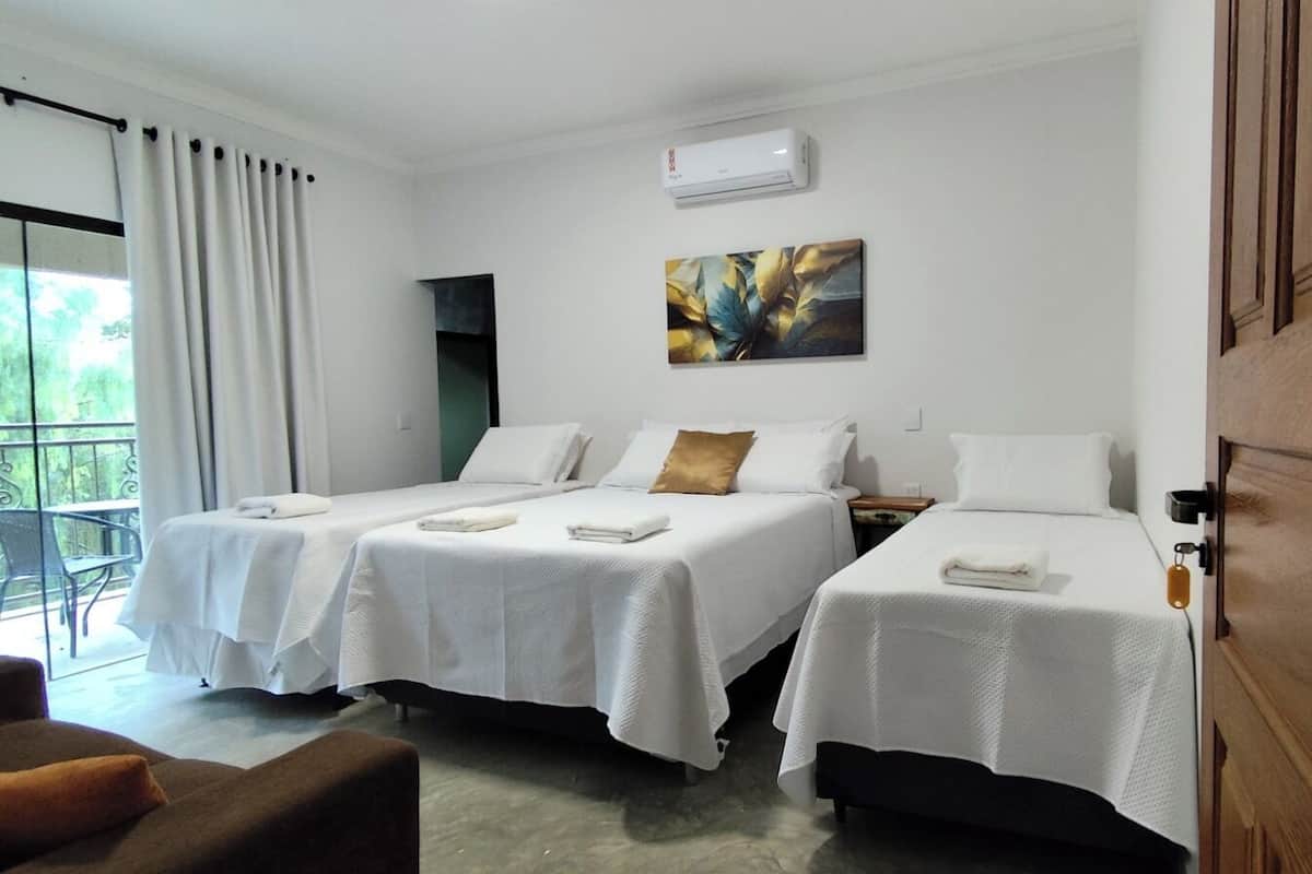 A hotel room with two beds, a balcony, and a painting on the wall.