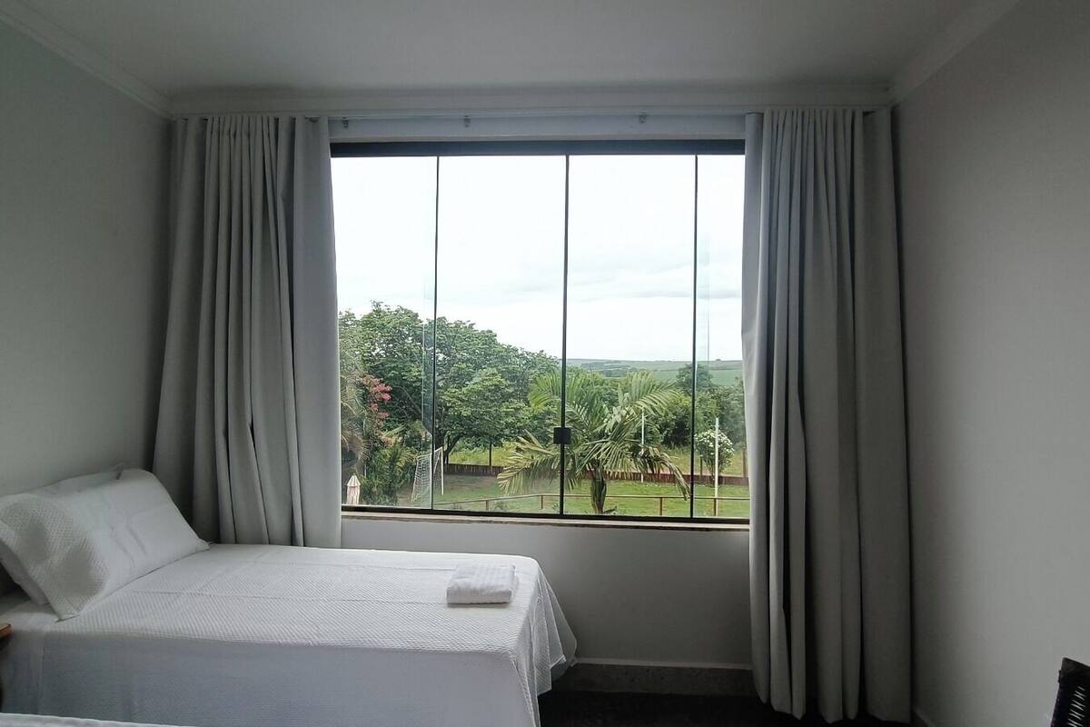 A hotel room with a bed, a nightstand, and a window with curtains.