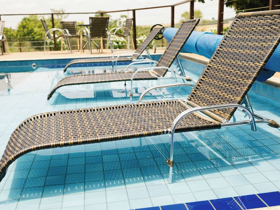 Un espace aménagé au bord de la piscine, avec des chaises longues et une table.