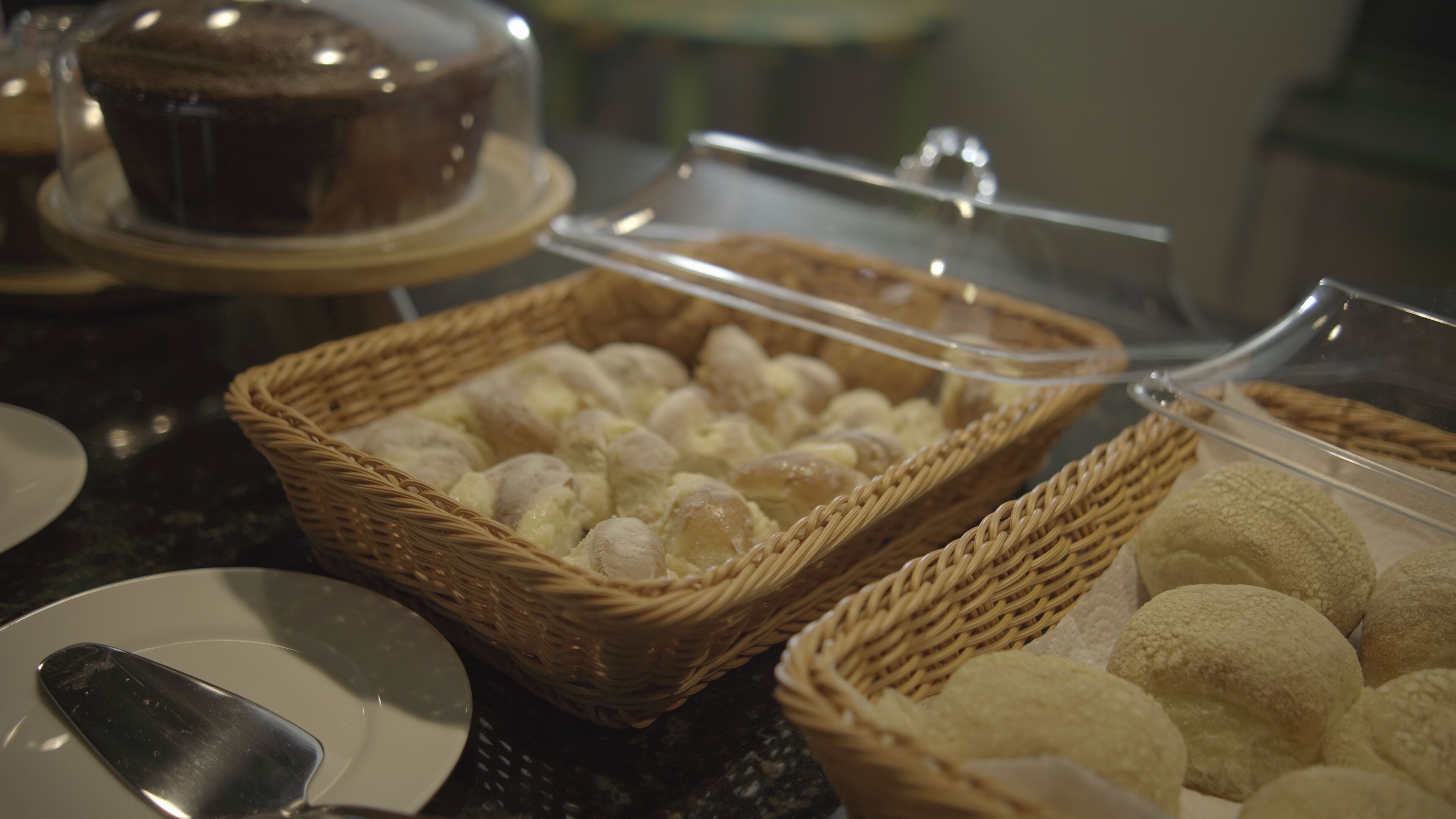 A buffet with various food items, including a cake and baskets of pastries.