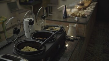 A buffet setup with various dishes and cooking equipment.