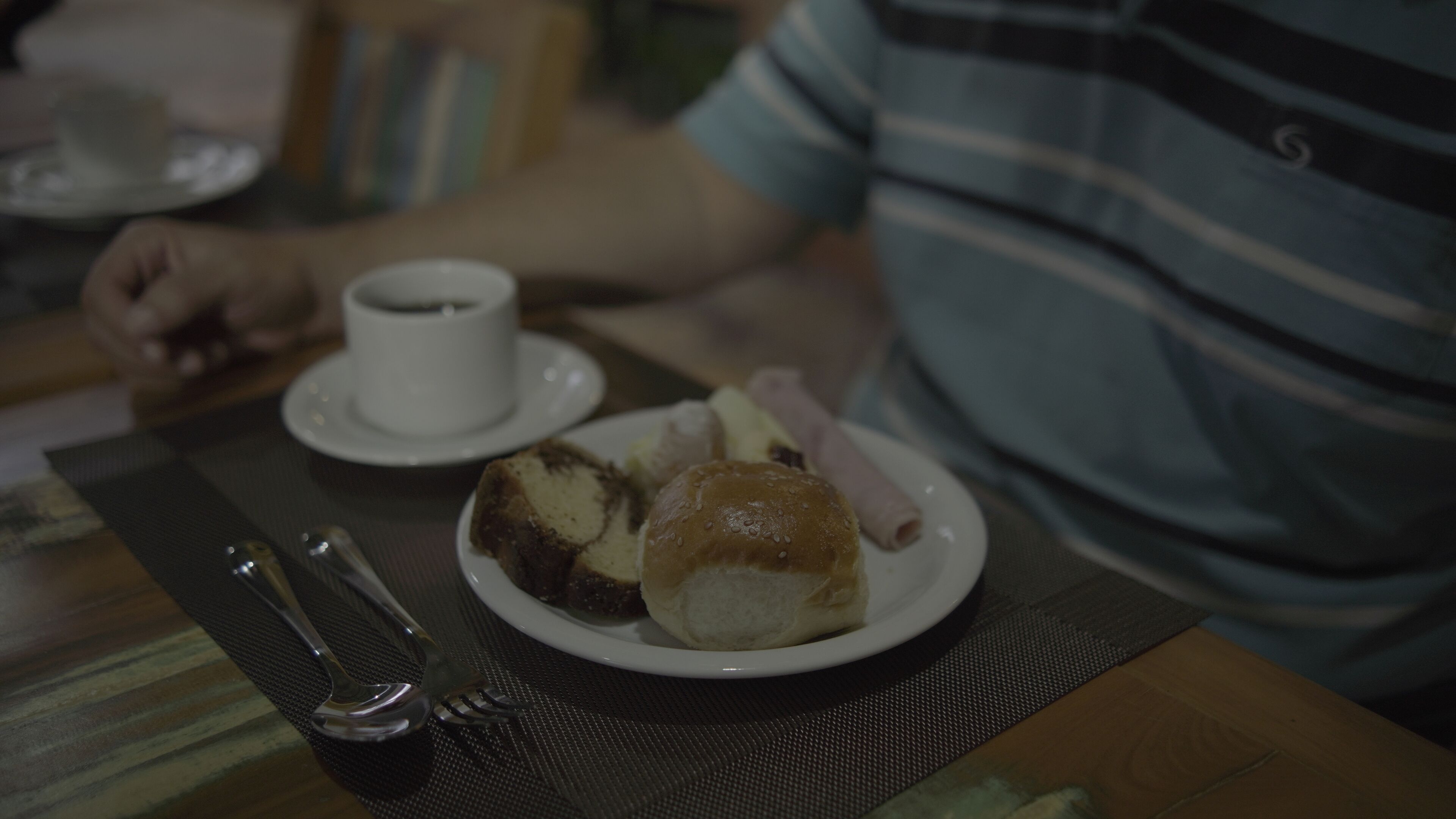 A dining table with a plate of food, a cup of coffee, and cutlery.