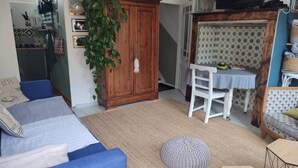 Ett mysigt vardagsrum med en blå soffa, ett träskåp och en matplats med en vit stol och ett vitt bord.