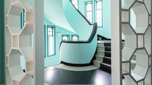 A modern interior with a spiral staircase, geometric shelving, and large windows.