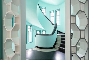 Ein modernes Interieur mit einer Wendeltreppe, geometrischen Regalen und großen Fenstern.
