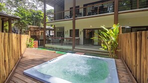 A hot tub on a wooden deck with a view of a building and outdoor furniture.
