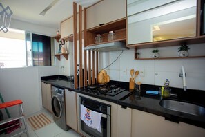 A compact kitchen with a gas stove, oven, washing machine, and a small sink.