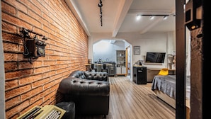 A modern living room with a brick wall, leather sofa, and a vintage telephone. - Palacete Riachuelo (São Paulo)