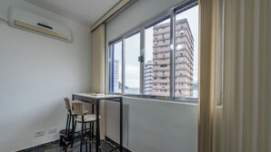 Una habitación pequeña con ventana, una mesa y una silla.