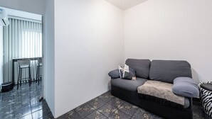 Una sala de estar moderna con un sofá gris, un tapete estampado y una pequeña mesa con sillas.