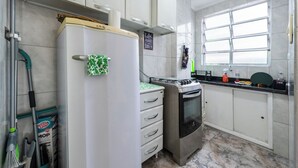Una cocina compacta con armarios blancos, horno integrado y refrigerador.