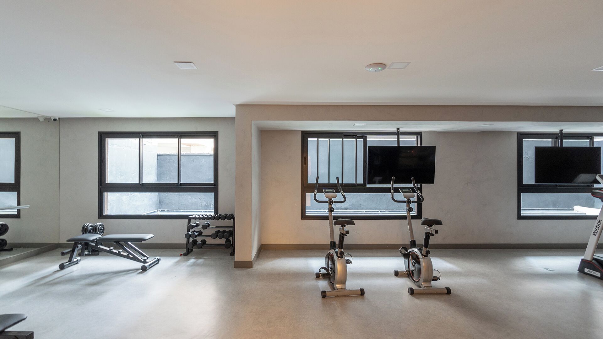 Un gimnasio amplio con equipo de cardio, máquinas de pesas y mancuernas.