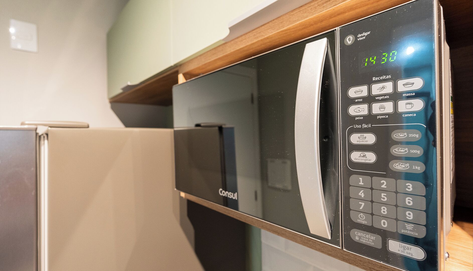 Een magnetron met een digitaal display en keypad, geplaatst op een houten aanrecht.