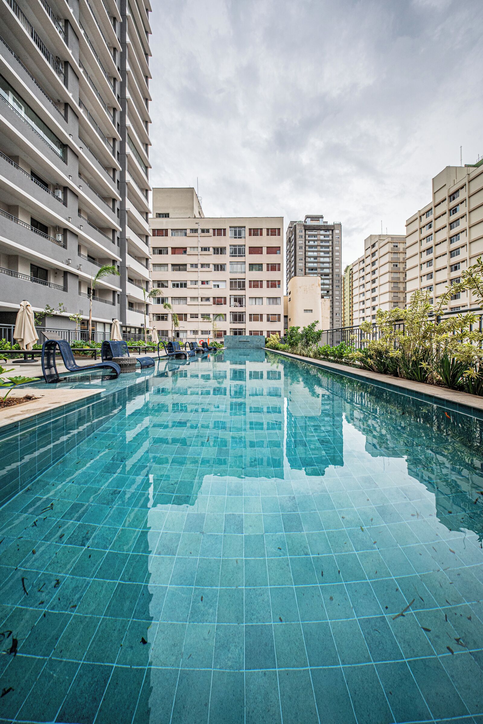 A swimming pool with lounge chairs and a view of high-rise buildings.