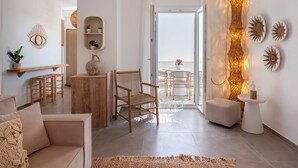 Een moderne woonkamer met een bank, een houten stoel, een kleine tafel en een balkon met een tafel en stoelen.
