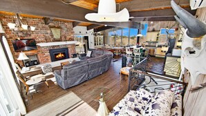 A cozy living room with a fireplace, leather sofa, and rustic decor. - Spacious Mountain-View Chalet | Walk to BM | Spa (The Blue Mountains)
