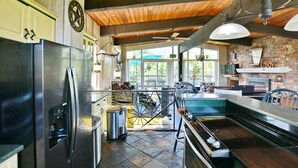 A kitchen with a stainless steel refrigerator, a stove, and a large window. - Spacious Mountain-View Chalet | Walk to BM | Spa (The Blue Mountains)