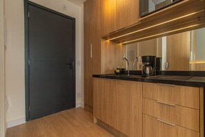 Eine moderne Küche mit Holdekor-Schränken, einer schwarzen Arbeitsplatte, einer Kaffeemaschine und einer Mikrowelle über der Arbeitsfläche.