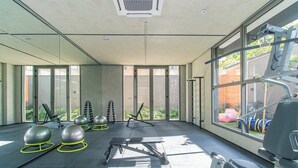 Et moderne fitnesscenter med træningsudstyr, store vinduer og udsigt til det fri.