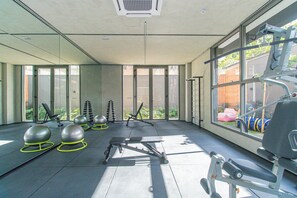 Ein modernes Fitnessstudio mit Trainingsgeräten, großen Fenstern und Blick ins Freie.