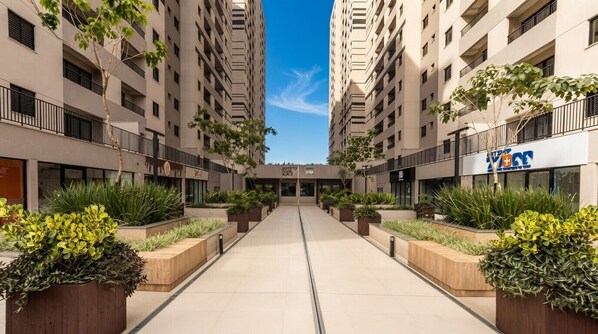 Un bâtiment moderne à étages, doté d’un couloir central et de jardinières agrémentées de plantes vertes.